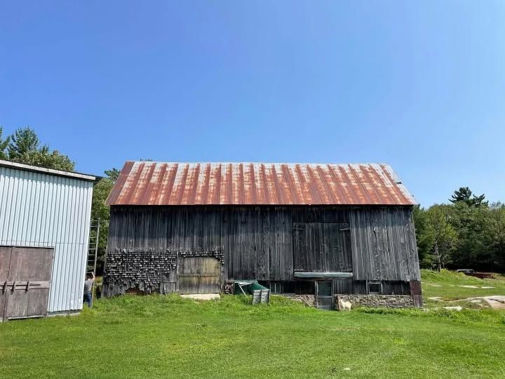Weathered gray bank barn with a rusted red metal roof